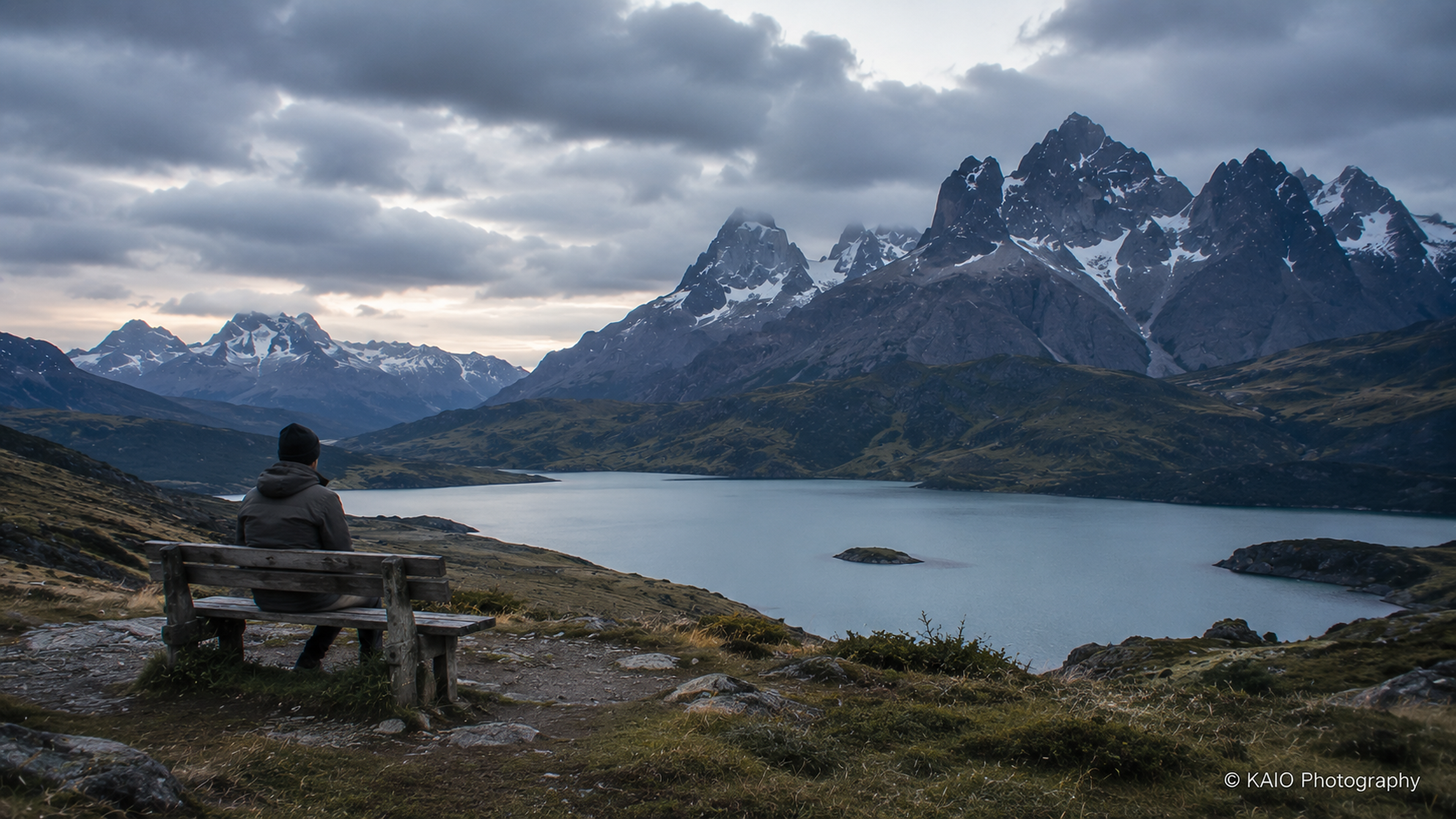 Person sitting before a remote mountain landscape